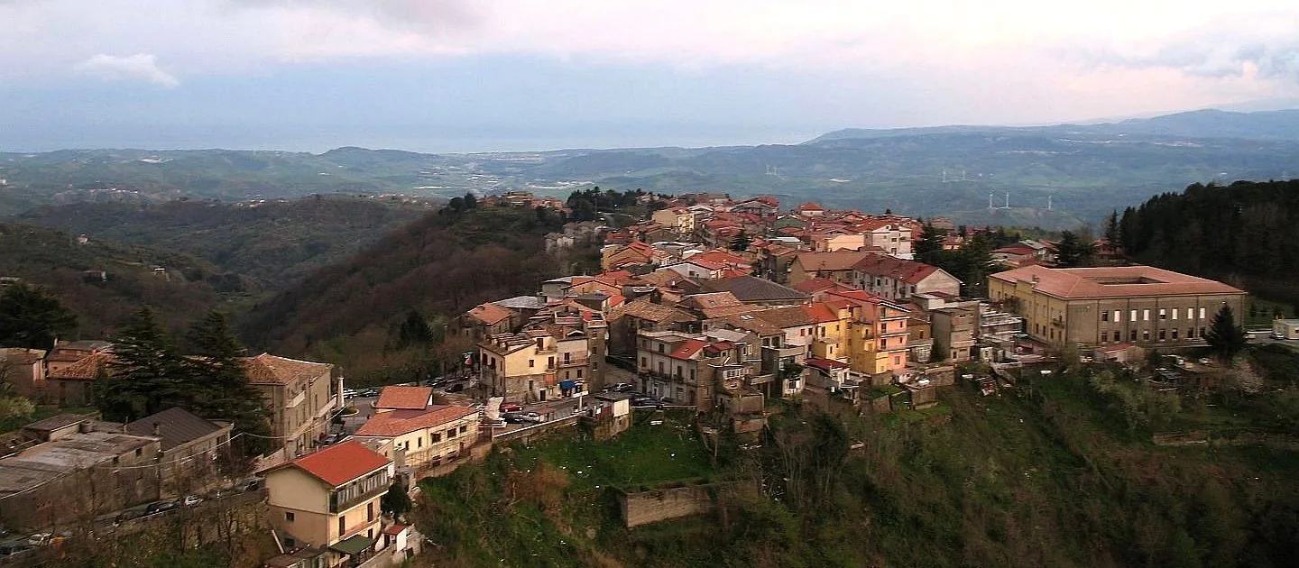 Veduta dall'alto delle case di Tiriolo su un crinale, con colline verdi e la linea del mare all'orizzonte